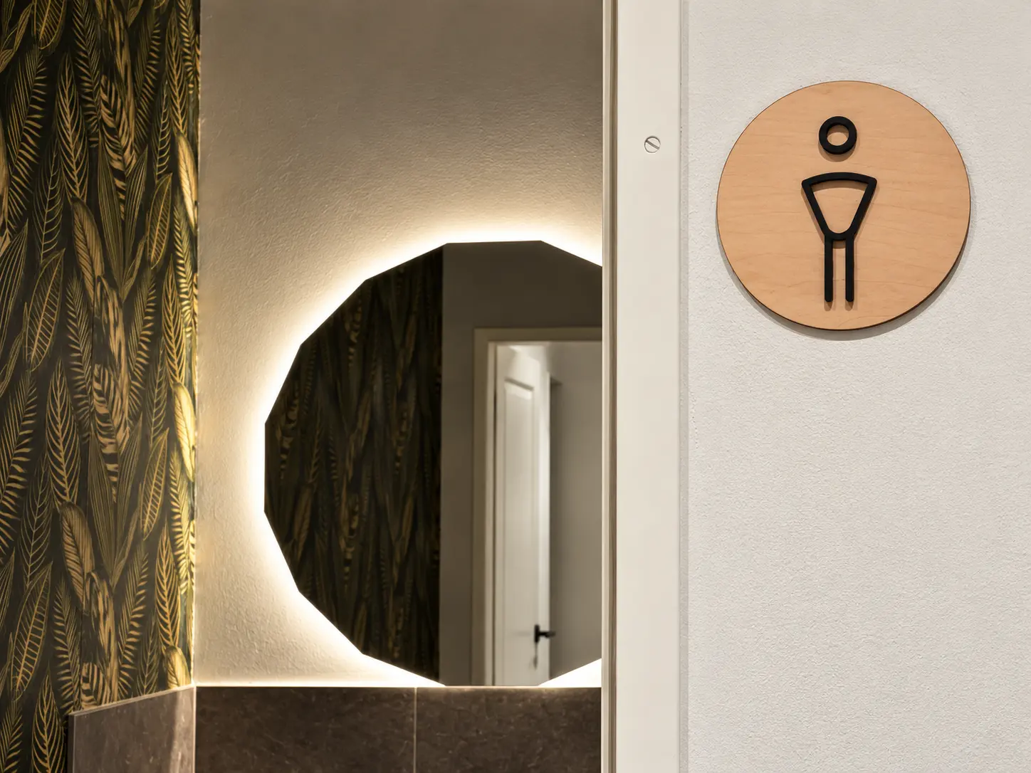 WC-Schild aus Holz neben beleuchtetem Spiegel